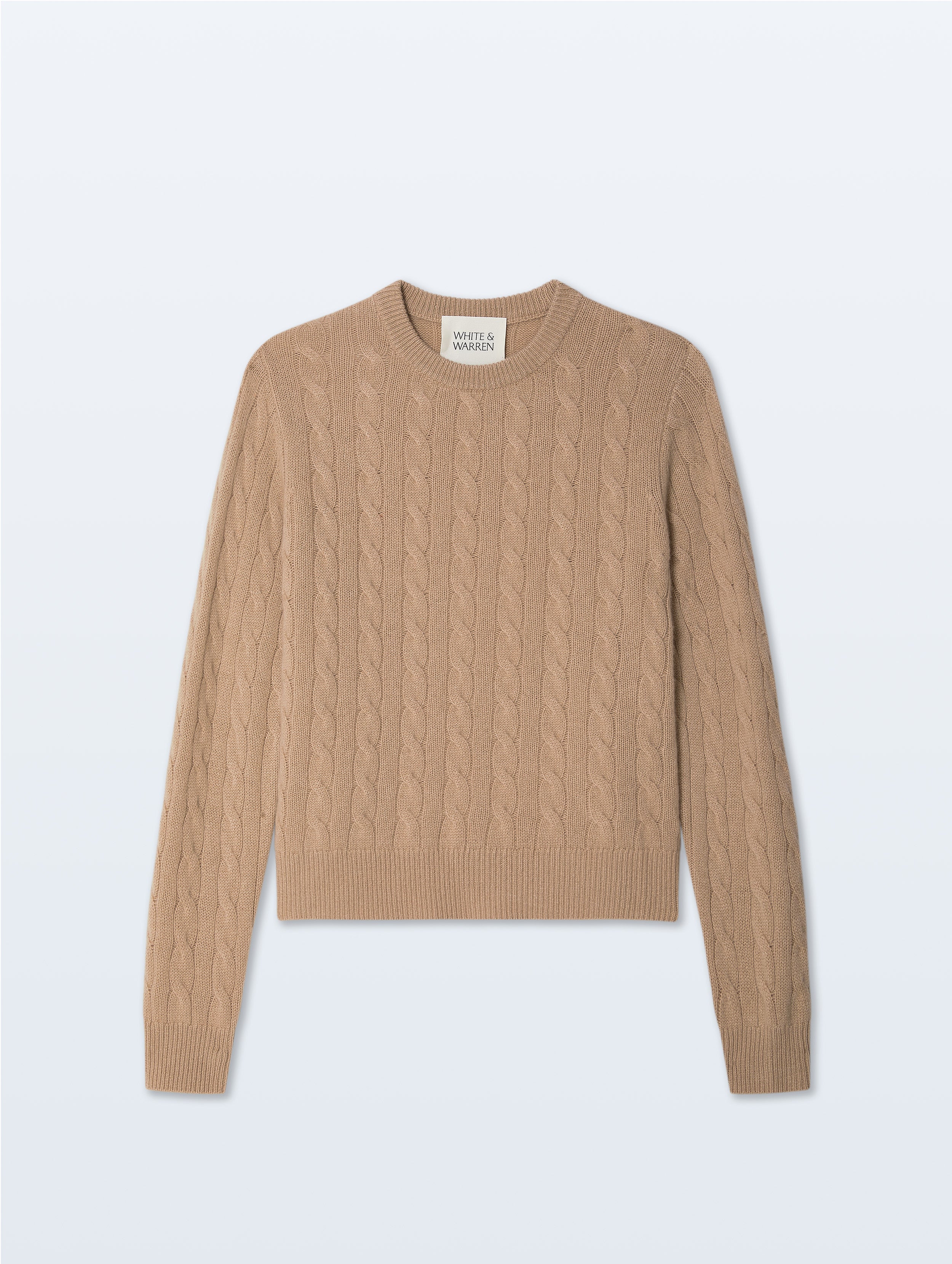 A cropped cable-knit crewneck sweater in a warm camel beige color, displayed flat against a light gray background.