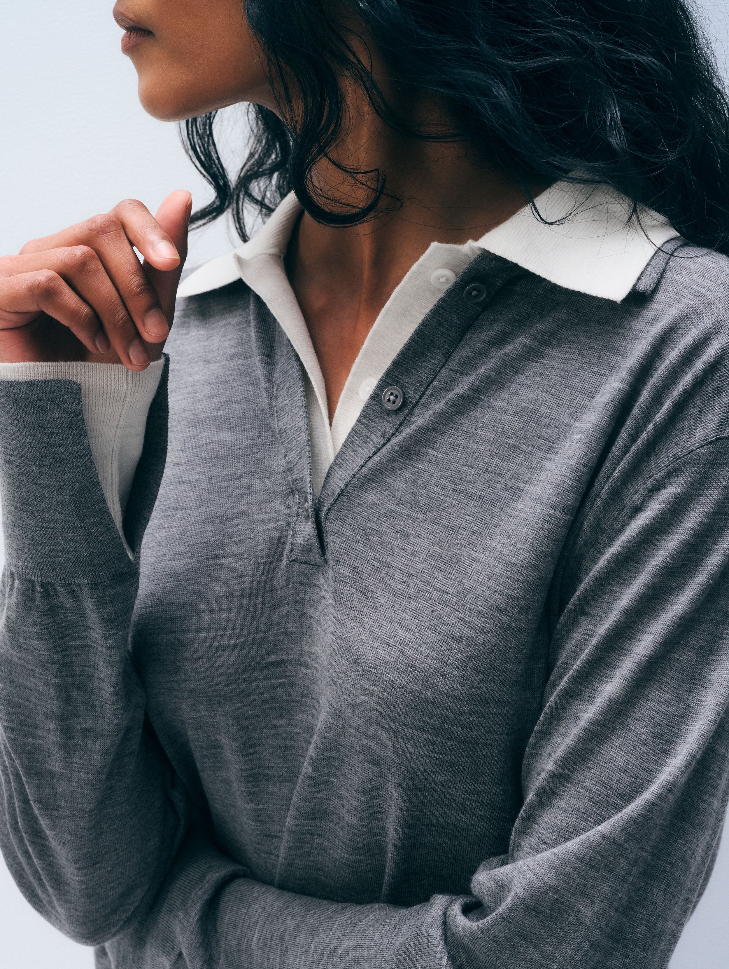 A close-up of a woman wearing a heather gray long-sleeve polo-style top with a contrasting white collar and white inner placket.