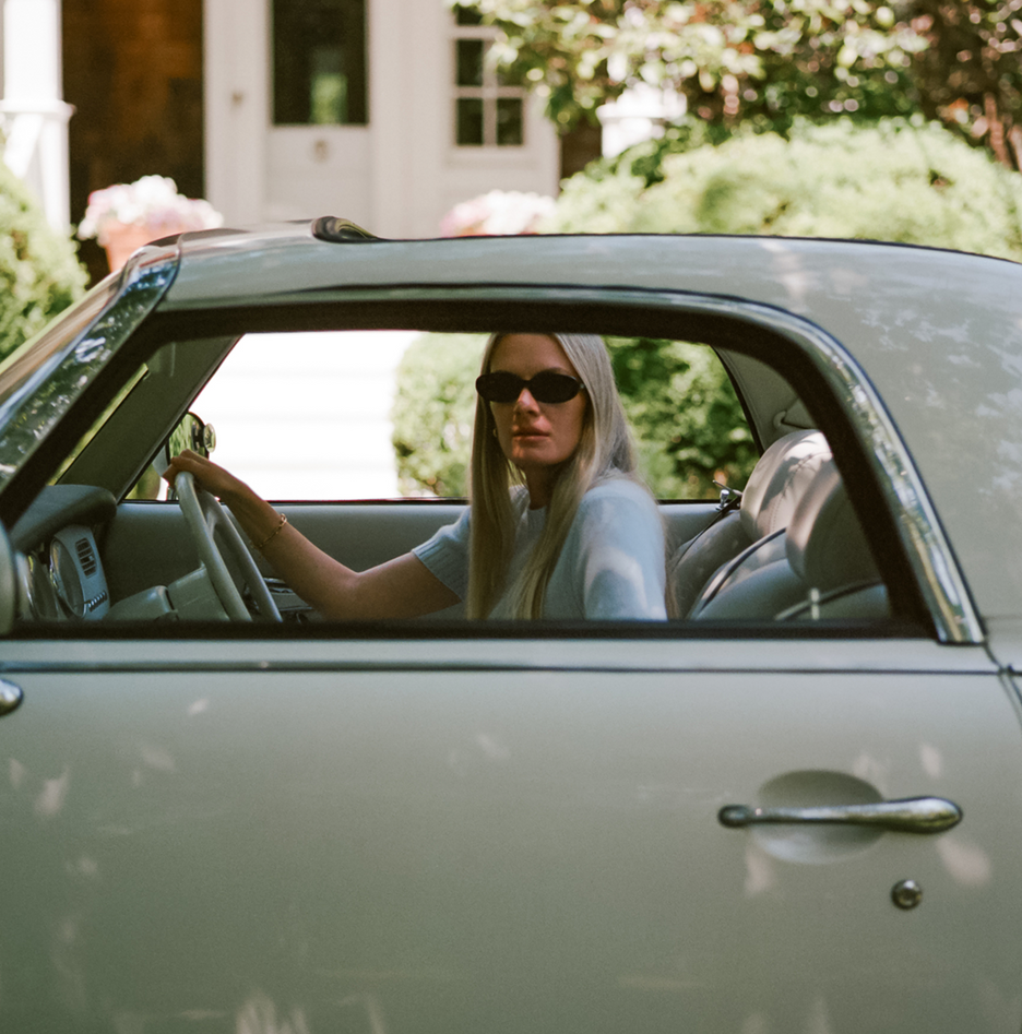 Woman sitting in a vintage car with a blurred background