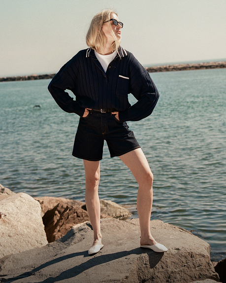 Woman wearing a polo while standing on rocks on the beach